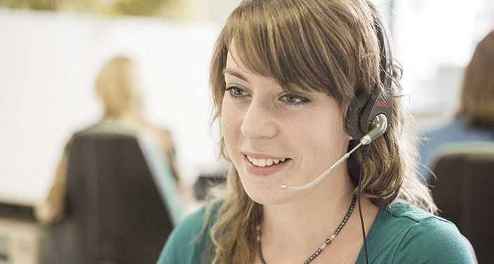 Call-Center-Mitarbeiterin mit Headset am Ohr